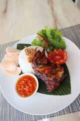 spicy chicken roasted with hot rice and raw vegetables,cucumbar,tomato, served on banana leaf