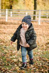 Autumn holiday in nature. Little girl walking in nature. Daughter walks in forest. Child running and playing on yellow leaves in park. Family with kid spending time together at sunset on vacation.