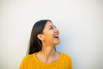 Close up young woman laughing and looking away by white background