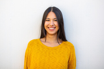 smiling young woman with long hair by white wall