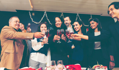 Group of cheerful friends celebrating new year indoors with drinks in hands. New Year celebration