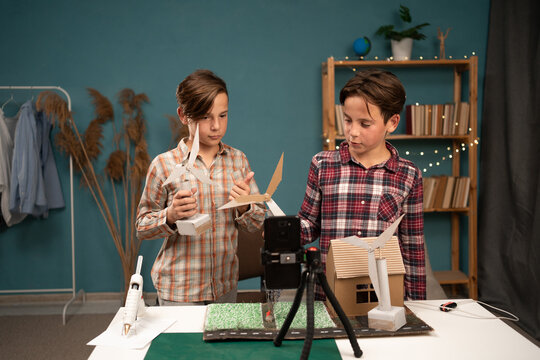 Children bloggers are preparing a school project at home on renewable energy sources by recording a video blog for social network subscribers. Smart modern kids and technology