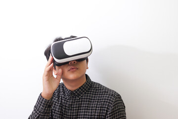 Portrait of Asian man in black plaid shirt using Virtual Reality (VR) glasses and looking up....
