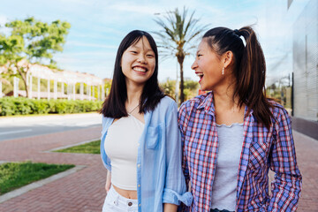 Obraz premium Happy beautiful chinese women friends bonding outdoors in the city - Playful pretty asian female adults meeting and having fun outside, concepts about lifestyle and friendship