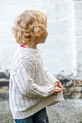 Despite the worry in their eyes, the child smiles sweetly while holding onto their clothes.