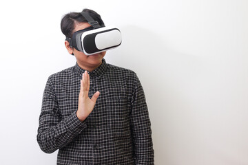 Portrait of Asian man in black plaid shirt using Virtual Reality (VR) glasses and greet his friend...