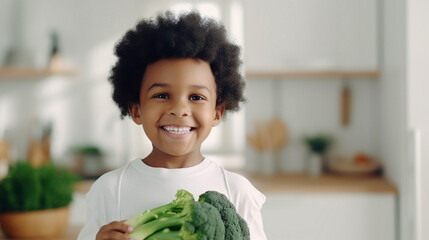 Little beautiful african boy posing with broccoli in the kitchen. Healthy vegan baby foods concept.