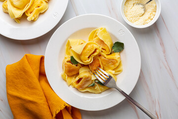Tortelloni or tortelli di zucca, italian pasta stuffed with pumpkin,  Ravioli served with butter and sage, parmesan cheese. Directly above. © Olga