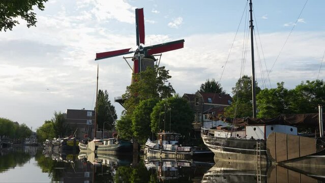 Scenic View Of Windmill de Roode Leeuw At Turfsingel With Anchored Vintage Boats In Gouda, Netherlands. Static Shot