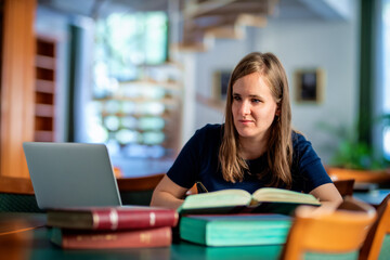A visually impaired young woman sitting and studying in the university library