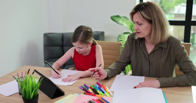 Happy family mother and daughter drawing together. Adult woman helps girl draw picture