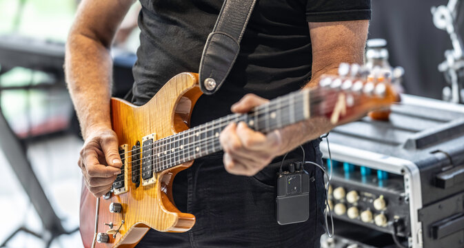 Guitarists play at a rock or rock n roll concert. A guitarist plays chords on an electric guitar