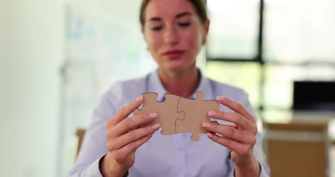Female hands holding two puzzle pieces closeup. Teamwork and unification