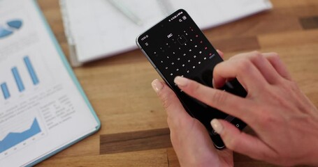 Woman uses calendar application on mobile phone in office. Future planning and agenda