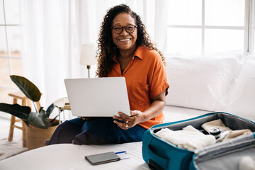Happy woman making travel bookings using a laptop, preparing for a solo vacation