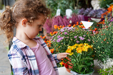 Cheerful cute child girl with curly hair choosing yellow flowers in the flower shop