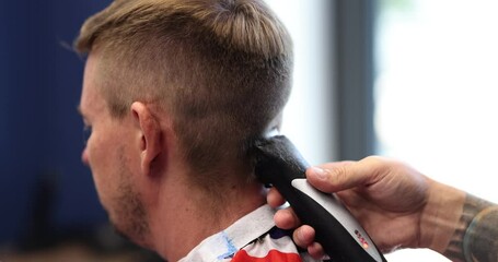 Fashionable hairdresser cuts man hair with hair clipper in barbershop. Man hairstyle and haircut in salon