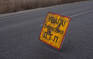 A red and orange emergency stop sign stands on an asphalt road in cloudy weather. Dramatic background, cold colors. Concept of safe driving on the road
