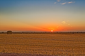 Sunrise over field after stubble has been made into bales of hay near Vredenburg, Western Cape,...
