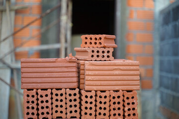 A stack of red clay bricks for construction waiting to be used.