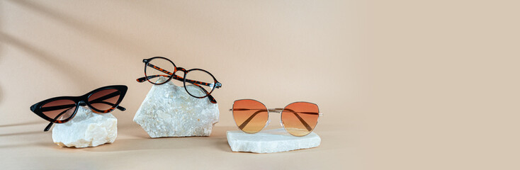 Sunglasses and glasses sale banner. Trendy sunglasses on stones on a beige background with shadows....