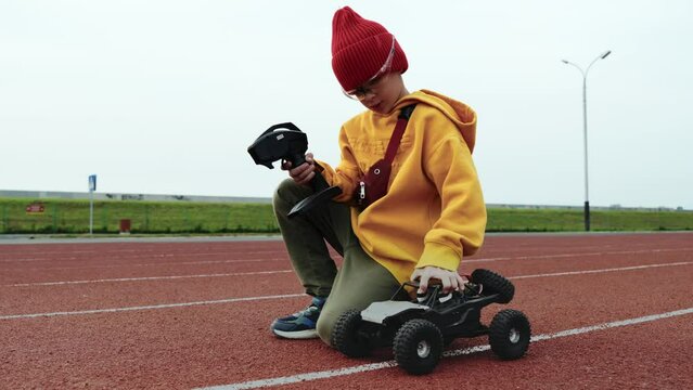 The boy holds in his hands and launches a radio-controlled model of a buggy car on a special track. Close-up of a radio-controlled vehicle.