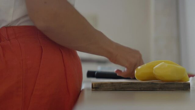 Close up of a woman holding potatoes and wiping up the cutting board. Panasonic Lumix S5 with a 75mm lens.