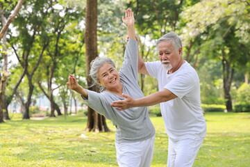 Naklejka na ściany i meble Asian senior couple practice yoga excercise, tai chi tranining, stretching and meditation together with relaxation for healthy in park outdoor after retirement. Happy elderly outdoor lifestyle concept