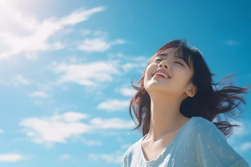 Poster Side view of a Japanese girl with a huge smile on her face arms wide open with eyes closed enjoying a beautiful sunny day again a blue sky © 1by1step