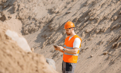 Engineer Worker use computer tablet for control quarry industrial excavator on construction site or...