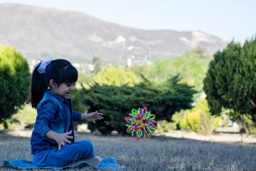 Little girl playing with a ball of many colors.