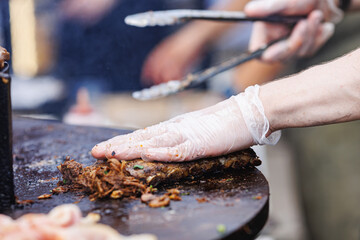 Cook grills steaks and pork ribs open fire. Turns meat over with tongs. Concept Street food