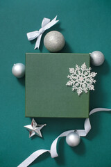 Simple but extremely beautiful green background with Christmas decoration concept. Baubles, ribbons and snowflakes of silver color stand out. Blank space for display product