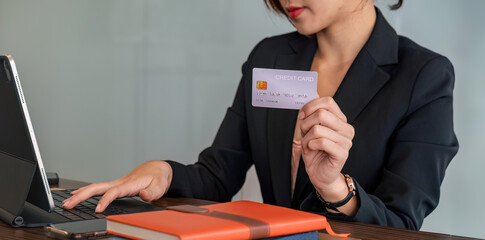 young Asian businesswoman enjoy shopping online using credit card at co-working