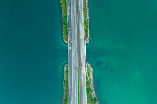 Aerial view of vehicles driving on a road crossing the Lugano lake, Melide, Ticino, Switzerland.
