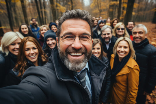 Cheerful man taking selfie with friends in woodland