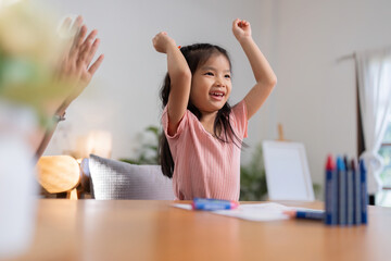 A little girl is happy to finish a draw with her mother in the living room at home. Excited mother...