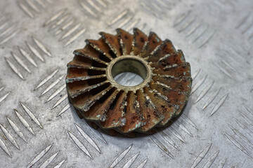 Bronze centrifugal pump impeller worn out by cavitation on metal table.