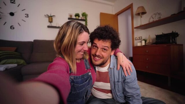 Excited video call young adult Caucasian couple talking cheerful to camera and holding positive pregnancy test. Cheerful man shows happy camera predictor. People in love waiting for baby at home. 