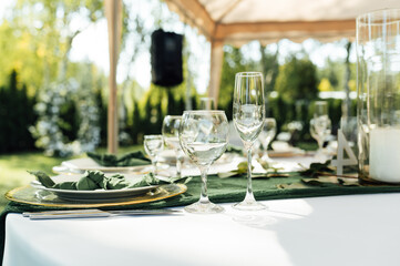 Open -air wedding banquet. The table is decorated with white plates and premium glasses for wine