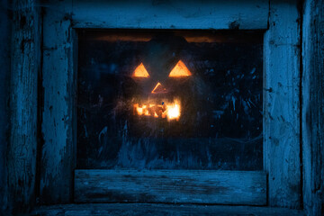 scary Halloween pumpkin glowing in window at night