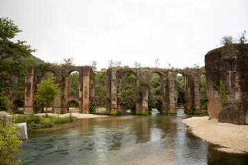 Ancient roman aqueduct with a river and plants at filipiada Greece summer natural light v8