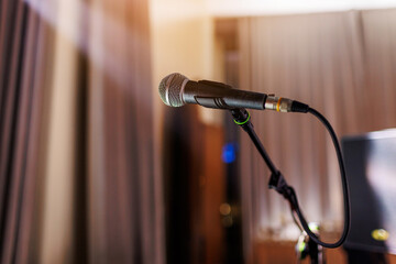 Microphone on stand on stage close up with searchlight light. Professional mic at concert hall or...