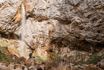 A male traveler enjoying near the mountain river waterfall.
