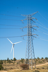 Vista de una torre electrica de alta tension y un aerogenerador en un parque eolico.
