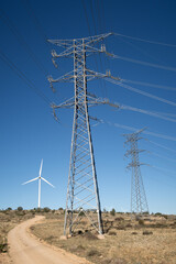Vista de una linea electrica de alta tension con aerogenerador en un parque eolico. - obrazy, fototapety, plakaty