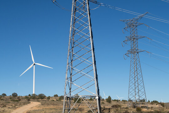 Vista de una linea electrica de alta tensi&oacute;n y un aerogenerador en un parque eolico.