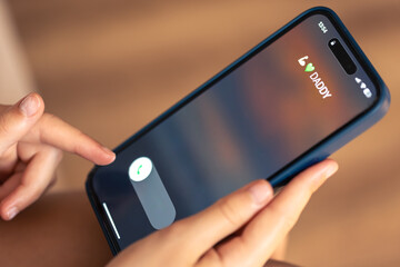 Close up of child hands holding phone with Dad's incoming call on display.