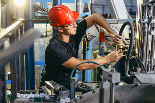 Factory worker working in industrial building indoor. Man fixing machines, checking work process, fixing techniciall problems