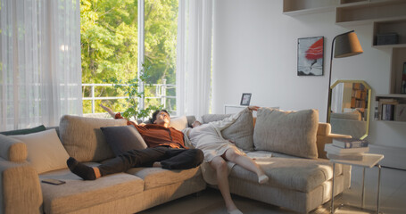Excited South Korean Couple Fall Down on a Comfortable Sofa in a Stylish Living Room While Smiling. Newly Wed Couple Enjoying Their Newly Purchased Furniture or Apartment
